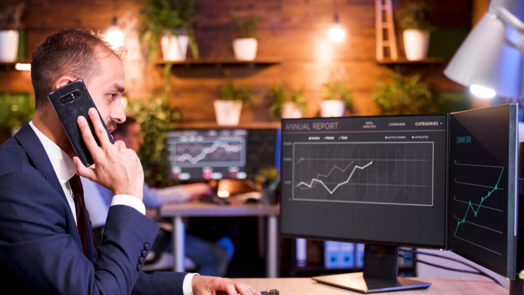 Mastering price action in volatile market 2025 businessman talking on the phone while working on the computer